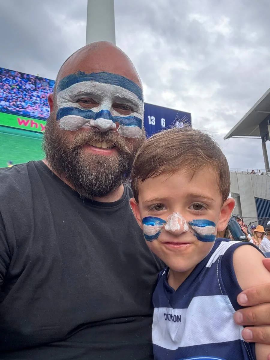Alex with his son, wearing Geelong colours at the football